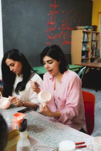 Women participate in an arts and crafts pottery class, painting ceramic bowls.